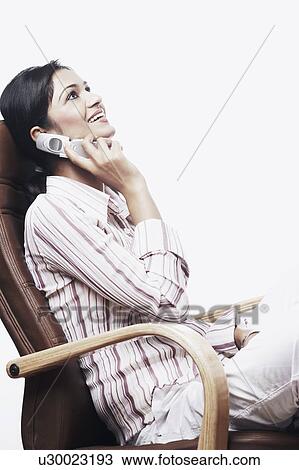 Stock Image - Side profile of a businesswoman talking on a mobile phone. Fotosearch