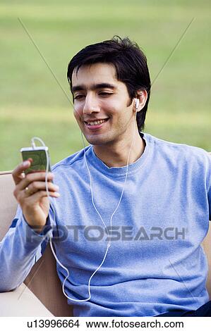 Young man listening to an MP3 player View Large Photo Image Picture - Young man listening to an MP3 player. Fotosearch