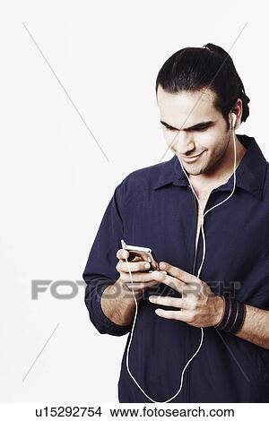 Young man listening to an MP3 player View Large Photo Image Picture - Young man listening to an MP3 player. Fotosearch