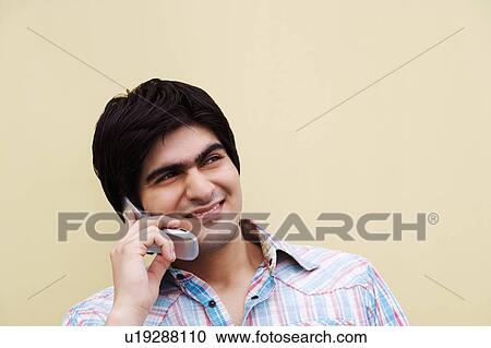 Stock Image - Young man talking on a mobile phone. Fotosearch