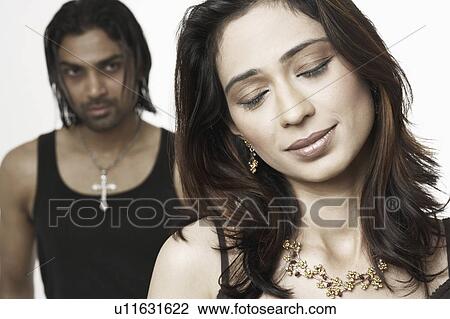 Close-up of a young woman with a young man standing behind her View Large Photo Image Stock Image - Close-up of a young woman with a young man standing behind her. Fotosearch