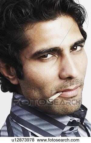 Stock Photo - Portrait of a young man with a bidi in his mouth. Fotosearch