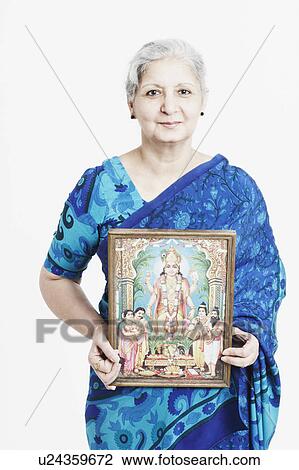 Stock Image - Portrait of a mature woman holding a religious picture. Fotosearch