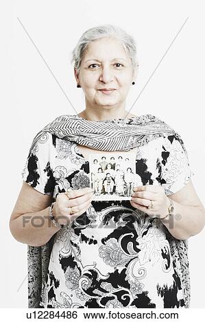 Portrait of a mature woman holding a photograph View Large Photo Image Stock Photograph - Portrait of a mature woman holding a photograph. Fotosearch