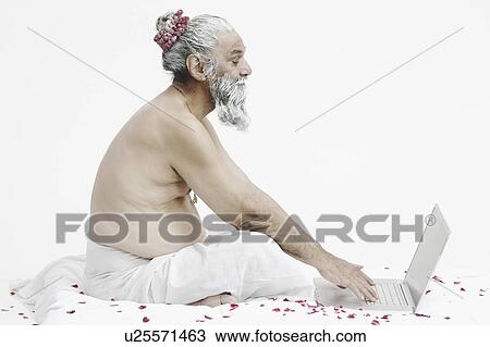 Stock Image - Side profile of a priest using a laptop. Fotosearch