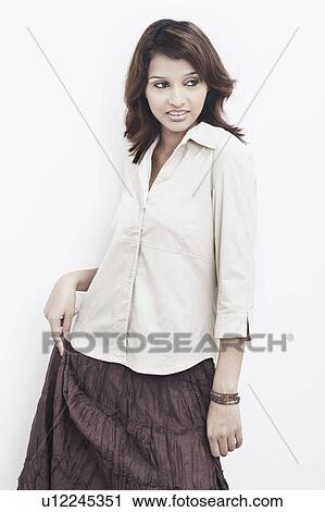Stock Image - Young woman standing and looking sideways. Fotosearch