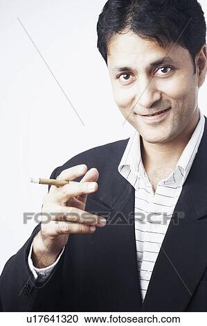 Portrait of a businessman holding a cigar View Large Photo Image Stock Image - Portrait of a businessman holding a cigar. Fotosearch
