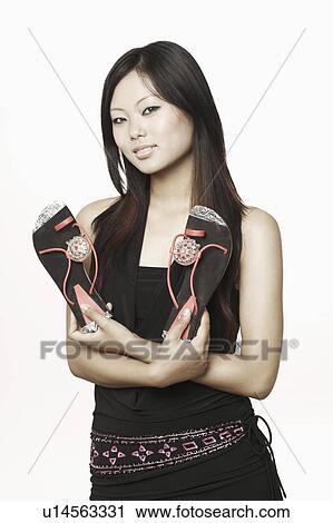 Portrait of a young woman holding a pair of sandals View Large Photo Image Stock Image - Portrait of a young woman holding a pair of sandals. Fotosearch