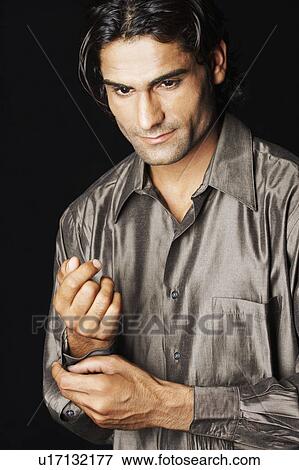 Stock Photo - Close-up of a young man buttoning his shirt. Fotosearch