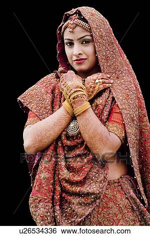 Stock Photograph - Portrait of a bride in a traditional wedding dress standing with her arms crossed. Fotosearch