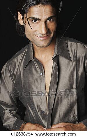 Picture - Portrait of a young man buttoning his shirt. Fotosearch
