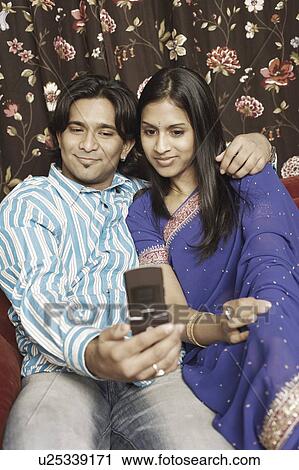 Stock Image - Close-up of a young couple taking a photograph of themselves. Fotosearch