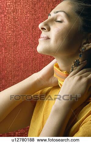 Stock Photo - Close-up of a young woman with her hand on her neck. Fotosearch