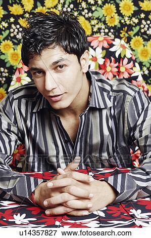 Stock Photo - Portrait of a young man sitting with his hands clasped. Fotosearch