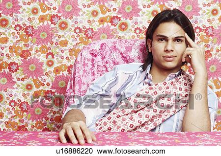 Stock Image - Portrait of a young man thinking with his finger on his temple. Fotosearch