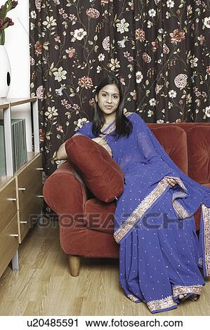Portrait of a young woman sitting on a couch View Large Photo Image Stock Image - Portrait of a young woman sitting on a couch. Fotosearch