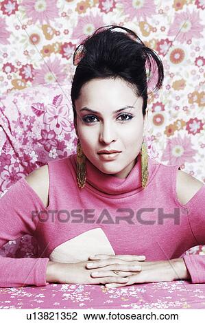 Stock Image - Portrait of a young woman sitting with her hands clasped. Fotosearch