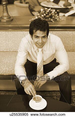 Stock Photography - High angle view of a businessman stirring a cup of tea with a spoon. Fotosearch