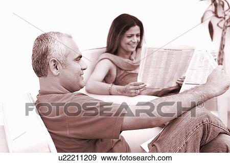 Mid adult couple reading newspapers and smiling View Large Photo Image Stock Photo - Mid adult couple reading newspapers and smiling. Fotosearch