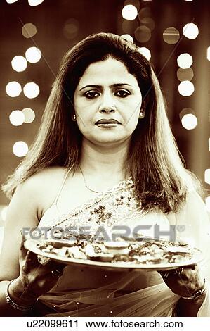 Portrait of a mid adult woman holding oil lamps and Rose petals in a plate View Large Photo Image Stock Image - Portrait of a mid adult woman holding oil lamps and Rose petals in a plate. Fotosearch