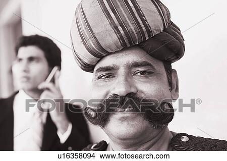 Picture - Portrait of a security guard with a businessman talking on a mobile phone behind him. Fotosearch