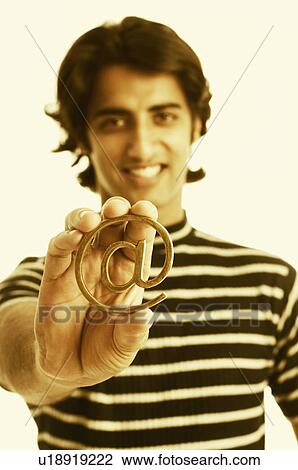 Portrait of a young man holding an At symbol View Large Photo Image Stock Image - Portrait of a young man holding an At symbol. Fotosearch