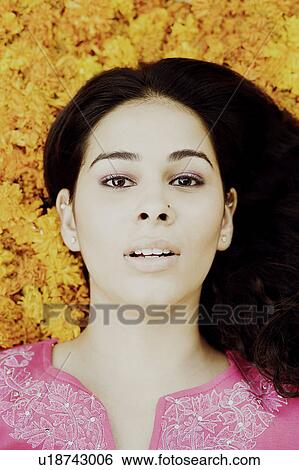 Stock Photograph - Portrait of a young woman lying on Marigolds. Fotosearch