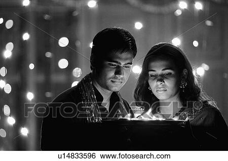 Young couple holding oil lamps in a plate View Large Photo Image Stock Photograph - Young couple holding oil lamps in a plate. Fotosearch