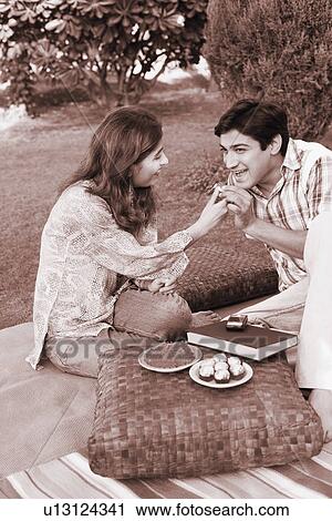 Stock Image - Young woman feeding a cookie to a young man. Fotosearch