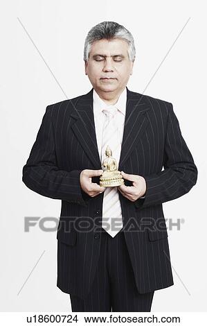 Close-up of a mature man holding an idol of Buddha View Large Photo Image Picture - Close-up of a mature man holding an idol of Buddha. Fotosearch