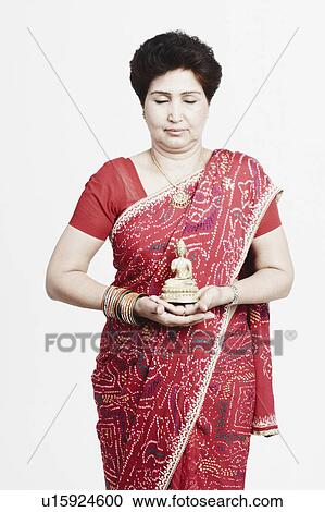 Stock Image - Close-up of a mature woman holding an idol of Buddha. Fotosearch