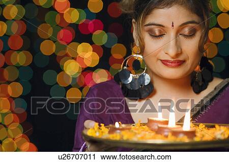 Close-up of a young woman holding a plate of religious offerings View Large Photo Image Stock Image - Close-up of a young woman holding a plate of religious offerings. Fotosearch