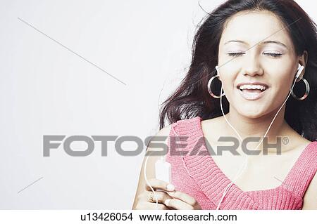 Close-up of a young woman with her eyes closed listening to an MP3 player View Large Photo Image Picture - Close-up of a young woman with her eyes closed listening to an MP3 player. Fotosearch