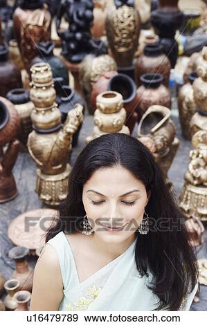 Stock Photo - High angle view of a young woman standing with her eyes closed in a pottery store. Fotosearch