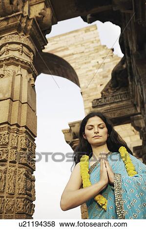 Stock Photo - Low angle view of a young woman praying with her eyes closed. Fotosearch