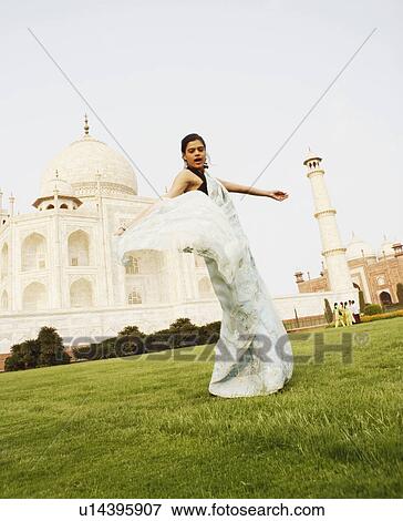 Stock Photo - Side profile of a young woman standing in front of a mausoleum, Taj Mahal, Agra, Uttar Pradesh, India. Fotosearch