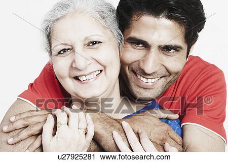 Stock Image - Close-up of a young man hugging his grandmother from behind. Fotosearch