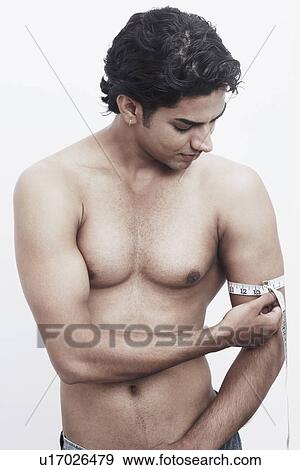 Close-up of a young man measuring his biceps with a measuring tape View Large Photo Image Stock Photo - Close-up of a young man measuring his biceps with a measuring tape. Fotosearch