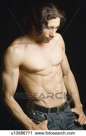 Stock Image - Close-up of a young man standing with his hands in his pockets. Fotosearch