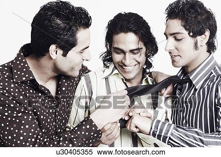 Close-up of two young men looking at a young man's tie View Large Photo Image Stock Photography - Close-up of two young men looking at a young man's tie. Fotosearch