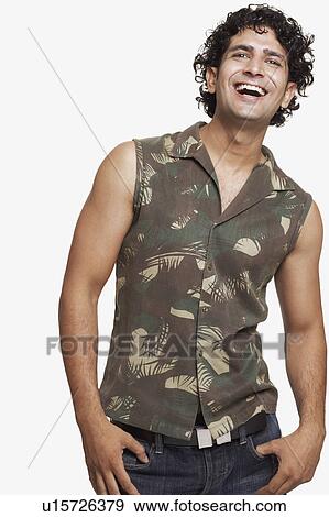 Stock Photo - Low angle view of a young man standing with his hands in his pockets. Fotosearch