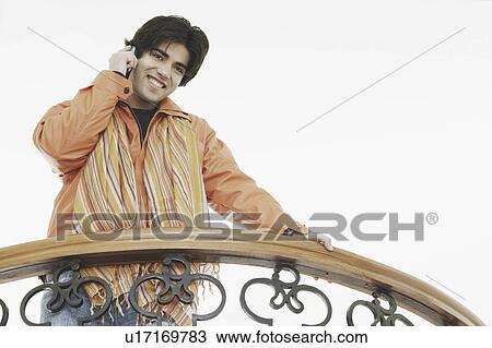 Low angle view of a young man talking on a mobile phone View Large Photo Image Stock Image - Low angle view of a young man talking on a mobile phone. Fotosearch