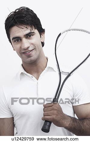 Stock Photo - Portrait of a young man holding a squash racket. Fotosearch
