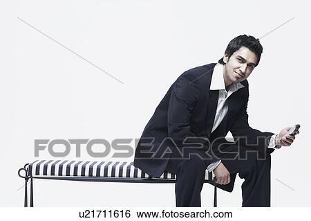 Stock Photograph - Portrait of a young man holding a mobile phone. Fotosearch