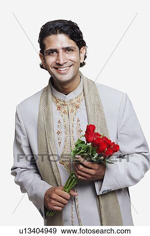 Portrait of a young man wearing a sherwani and holding a bunch of flowers View Large Photo Image Stock Photo - Portrait of a young man wearing a sherwani and holding a bunch of flowers. Fotosearch