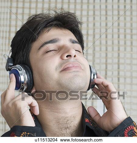 Close-up of a young man listening to music with his eyes closed View Large Photo Image Picture - Close-up of a young man listening to music with his eyes closed. Fotosearch