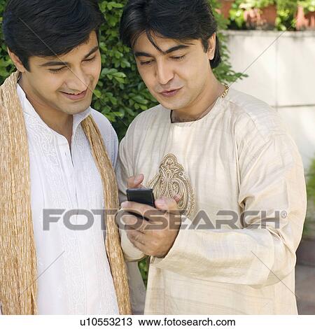 Stock Image - Close-up of a young man showing a mobile phone to another young man. Fotosearch
