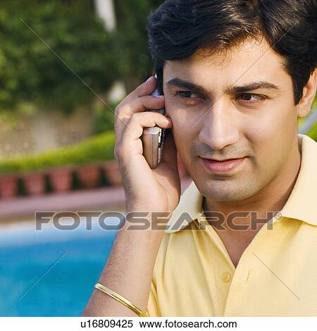 Stock Photography - Close-up of a young man talking on a mobile phone. Fotosearch