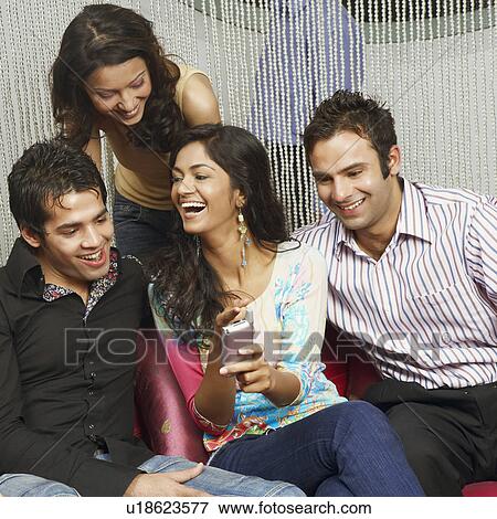 Close-up of a young woman showing a mobile phone to her three friends View Large Photo Image Stock Photo - Close-up of a young woman showing a mobile phone to her three friends. Fotosearch