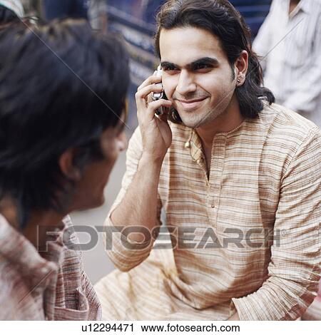Stock Image - High angle view of a young man talking on a mobile phone. Fotosearch